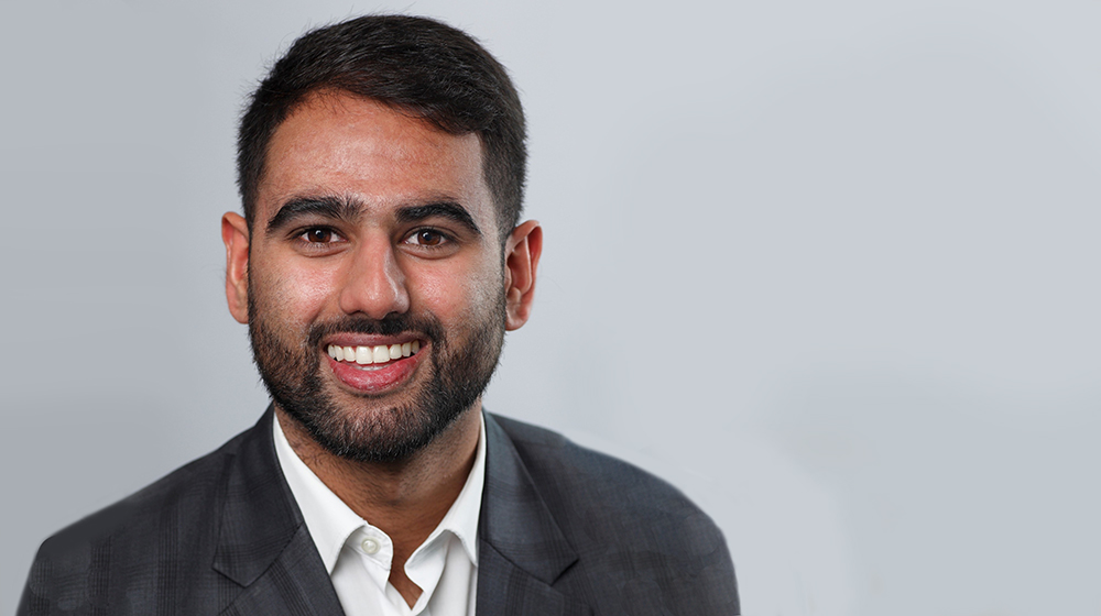 Next Gen MBA student Veerkanvar Cheema smiling in a suit against a gray backdrop.